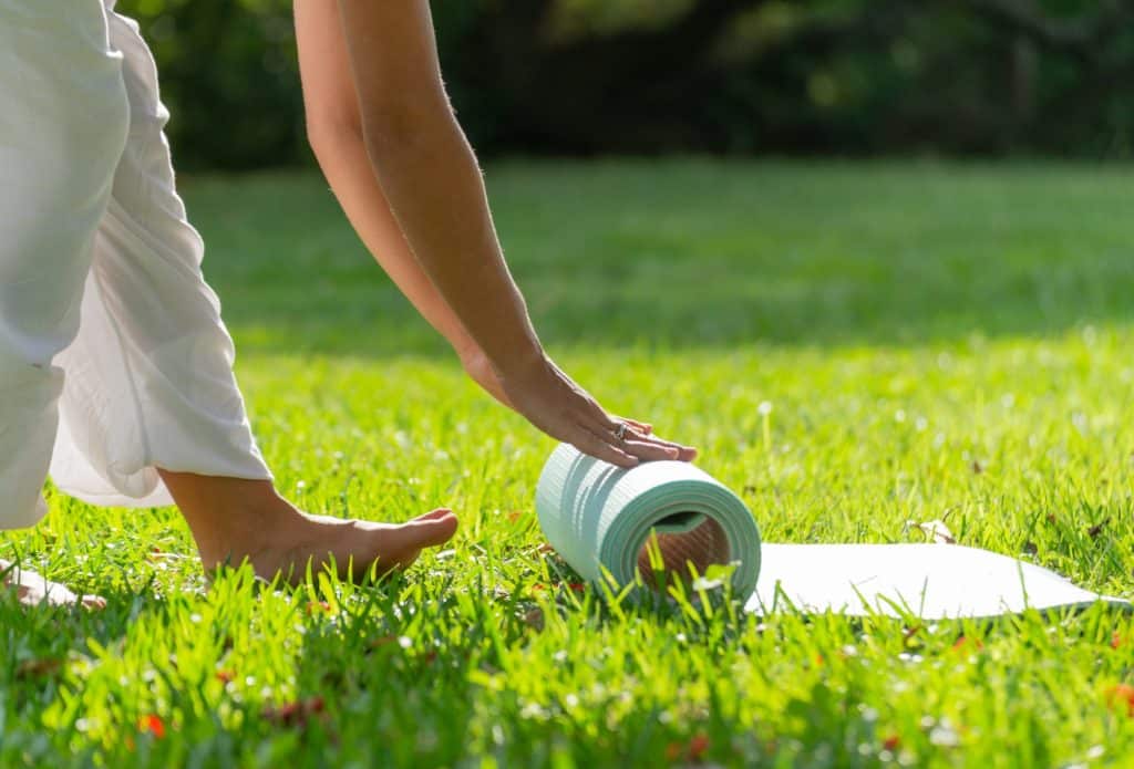 Young Woman Rolling Yoga Mat in a Green Park on a Sunny Day.Copy Space.Healthy Concept
